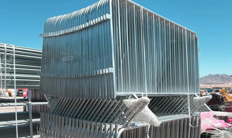 "Stack of metal crowd control barriers outdoors."