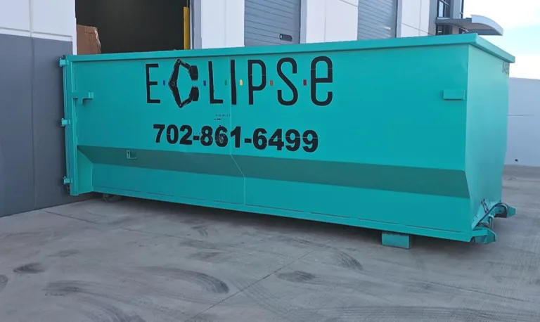 "Teal Eclipse dumpster placed outside a commercial building near loading docks."