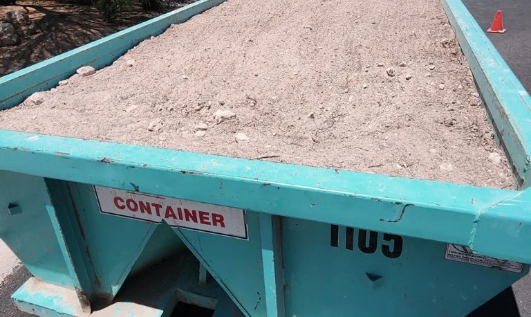 "Dumpster filled with dirt and rocks."